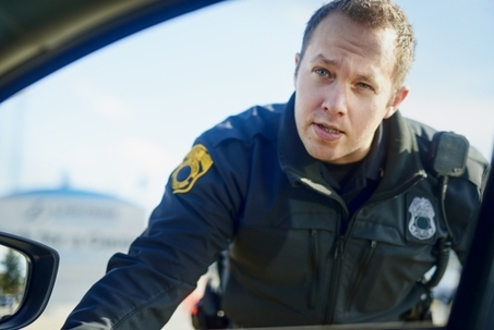 Traffic stop, police officer and talking at car for inspection, license check and law enforcement responsibility in city. Man, cop and question at vehicle window in roadblock, safety or investigation