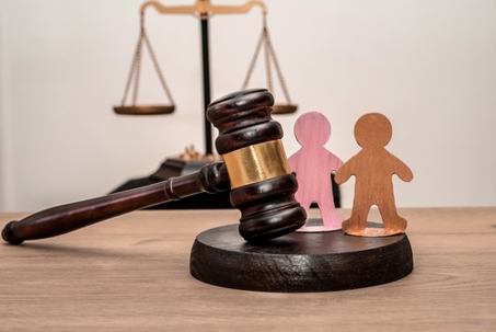Judge's gavel, scales of justice, and two wooden figures symbolizing children, family law, guardianship and protection of rights in civil court, legal inheritance