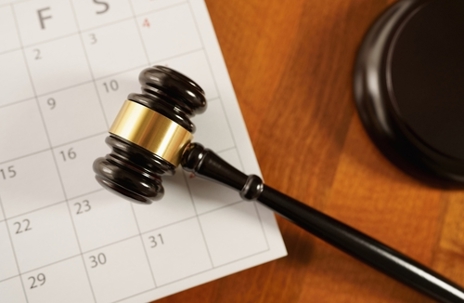 Law, legislation, justice and time concept with a close up top view of a judge gavel on a calendar page. Statute of limitations and prescriptive period deadline in legal proceedings conceptual images