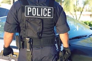 photo of a police officer, showing their back and the "police" spelled out on the back of their vest.